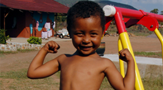 A boy standing outside flexing his muscles