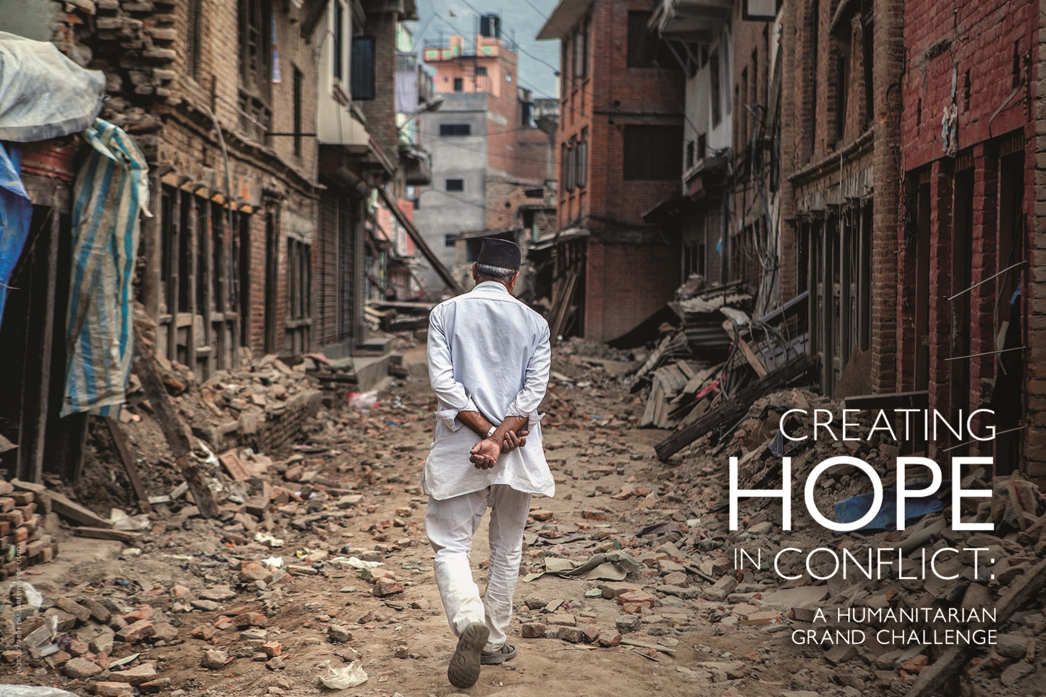 A man walks through a neighborhood surrounded by rubble with his hands crossed behind his back